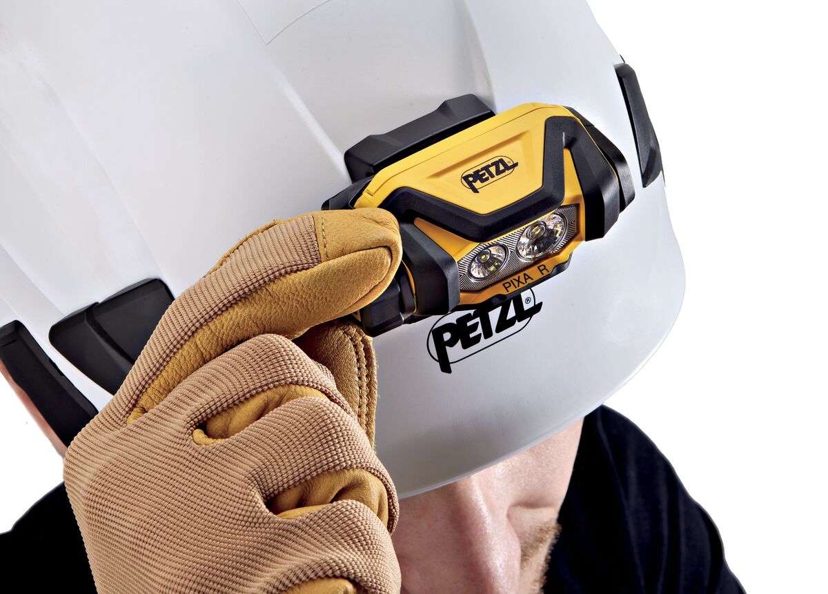Person wearing a helmet with a Petzl headlamp and a brown glove.