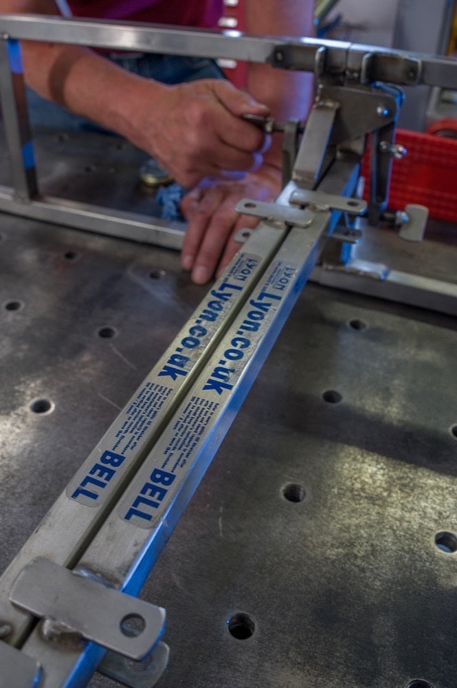 Person using a metal cutting machine with 'BETT' branding on a workshop table.