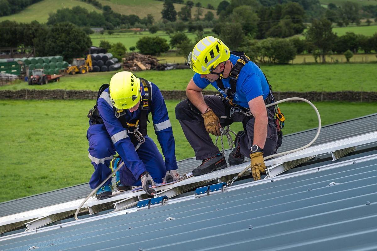Two workers in high-visibility safety gear on a roof.