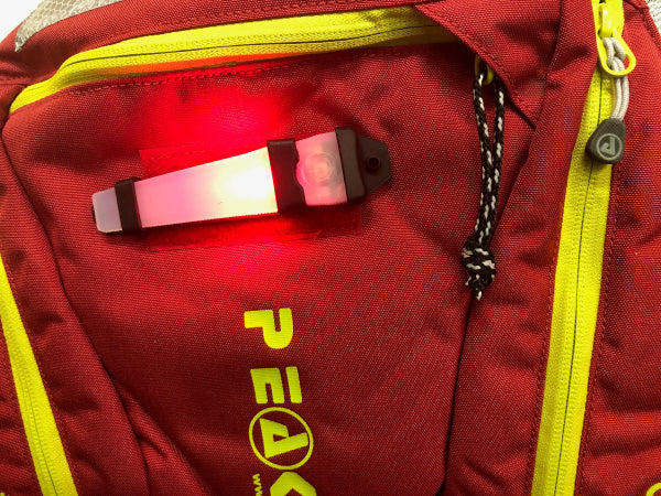 Red backpack with a visible brand logo and a light attached to it.