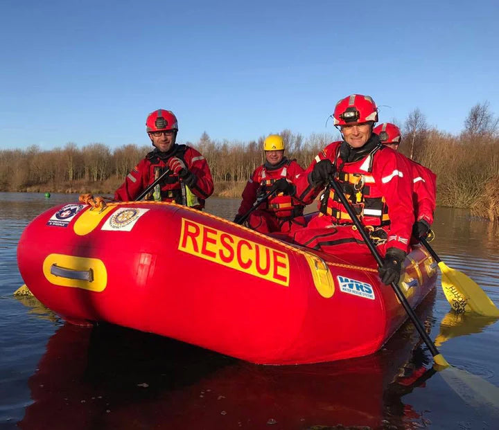Rescue team in red inflatable boat on water with clear sky