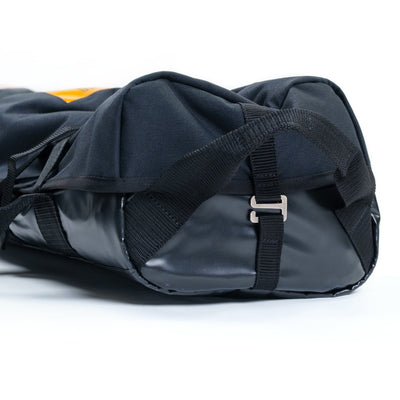 Black duffel bag with straps on a white background