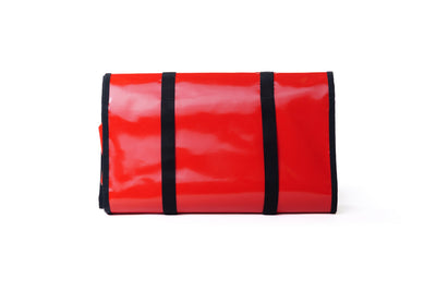 Red roll-up mat with black straps on a white background