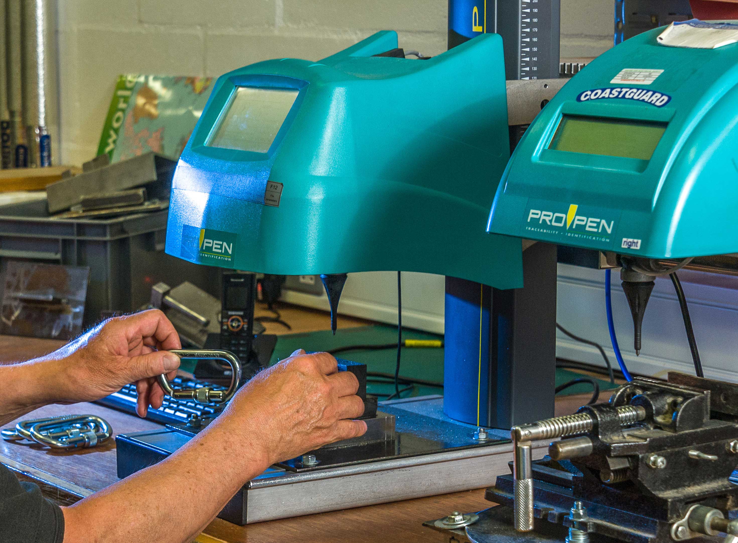 Person working with teal equipment labeled 'ProTape' and 'Coastguard' in a workshop setting.