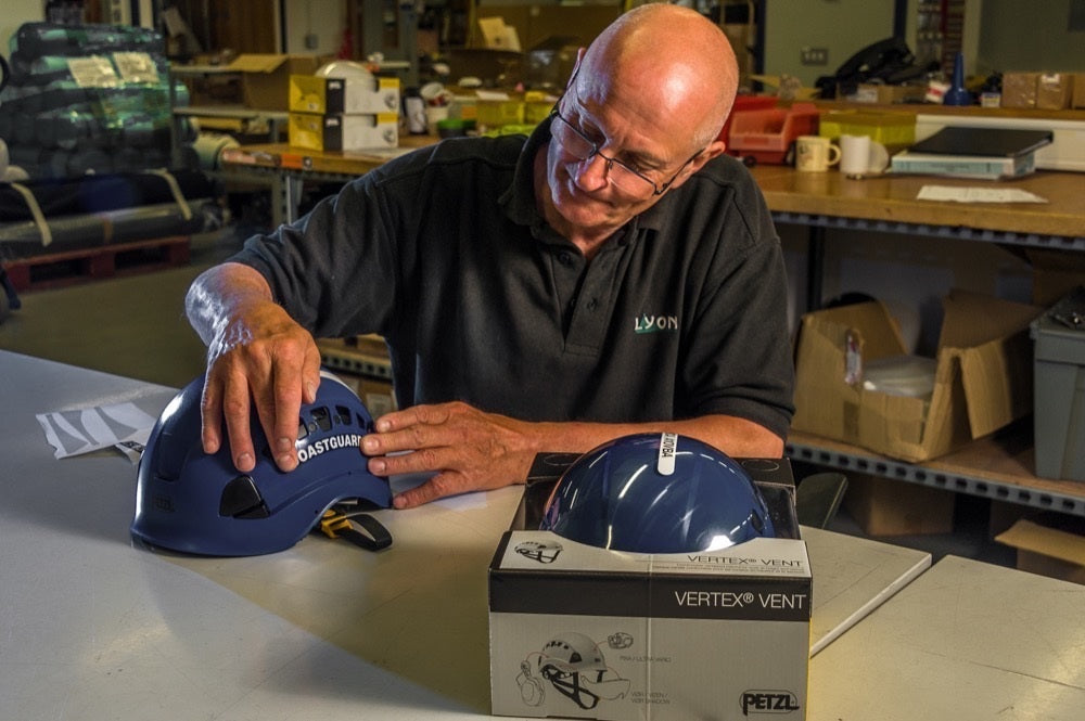 Man examining a blue helmet next to its box in a warehouse setting