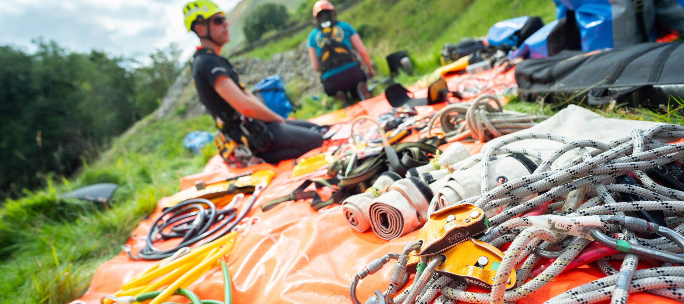 Person with safety gear and equipment on a grassy hillside