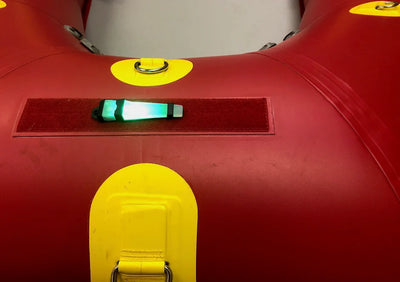 Close-up of a red inflatable boat with yellow handles and a green light.