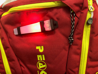 Red backpack with a visible brand logo and a light attached to it.