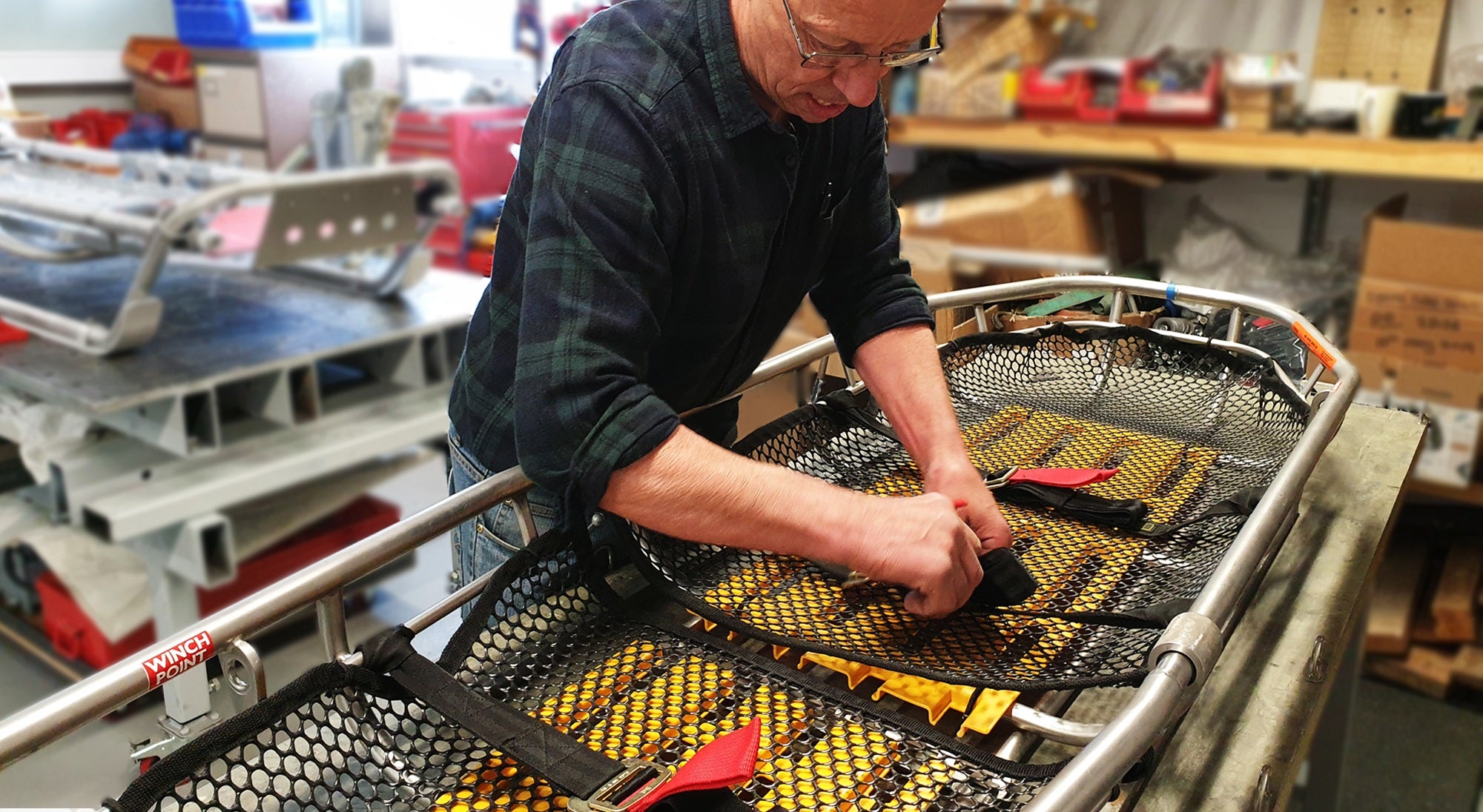 Person working on a metal frame with tools in a workshop setting