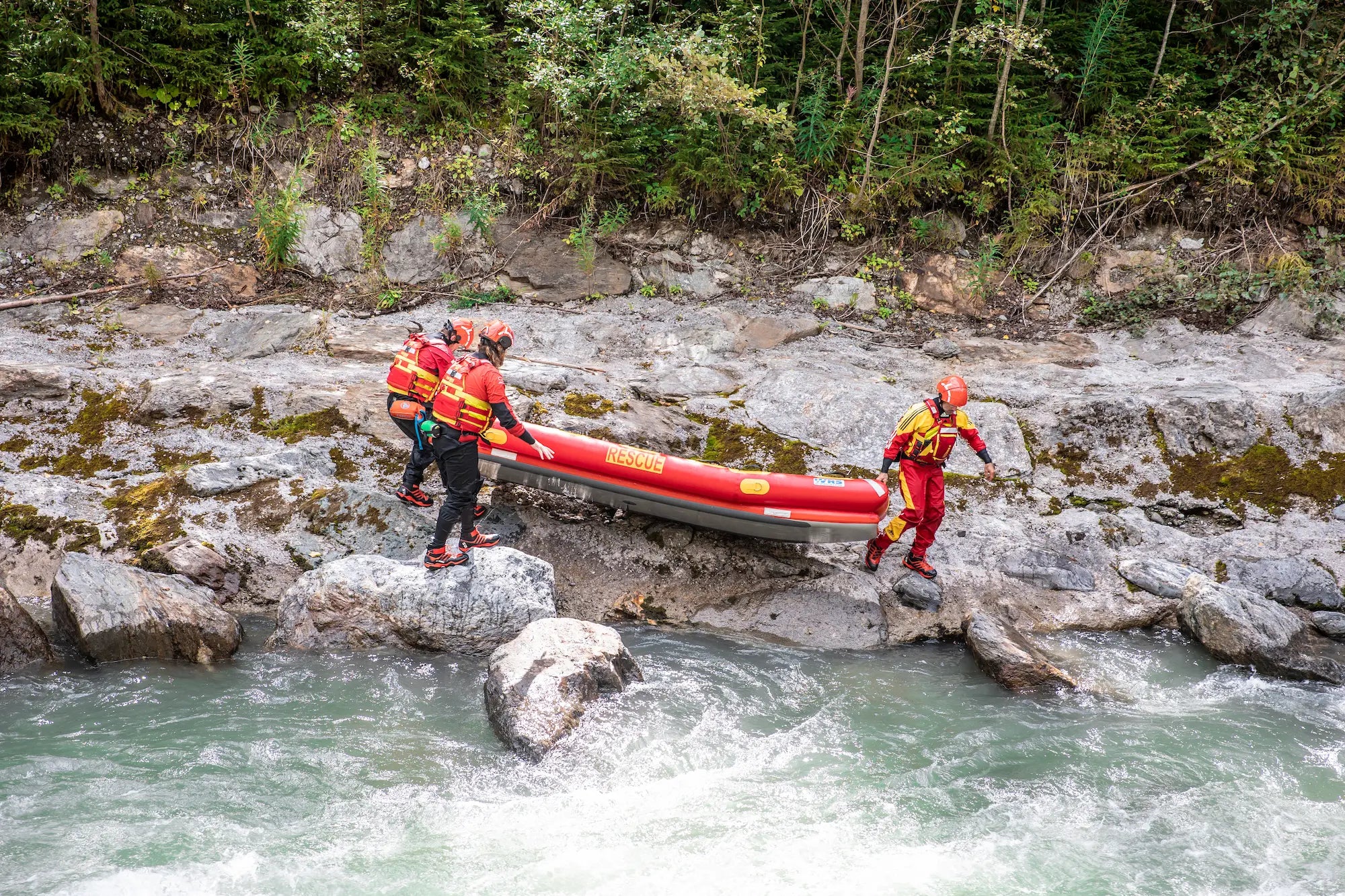 3 people carrying a rescue raft